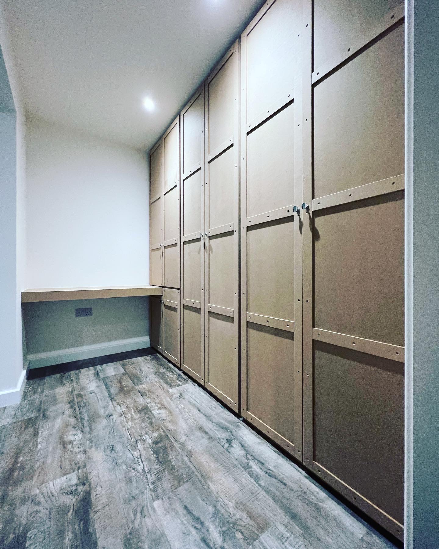 A full wall of grey shaker floor to ceiling cupboards with a built-in desk