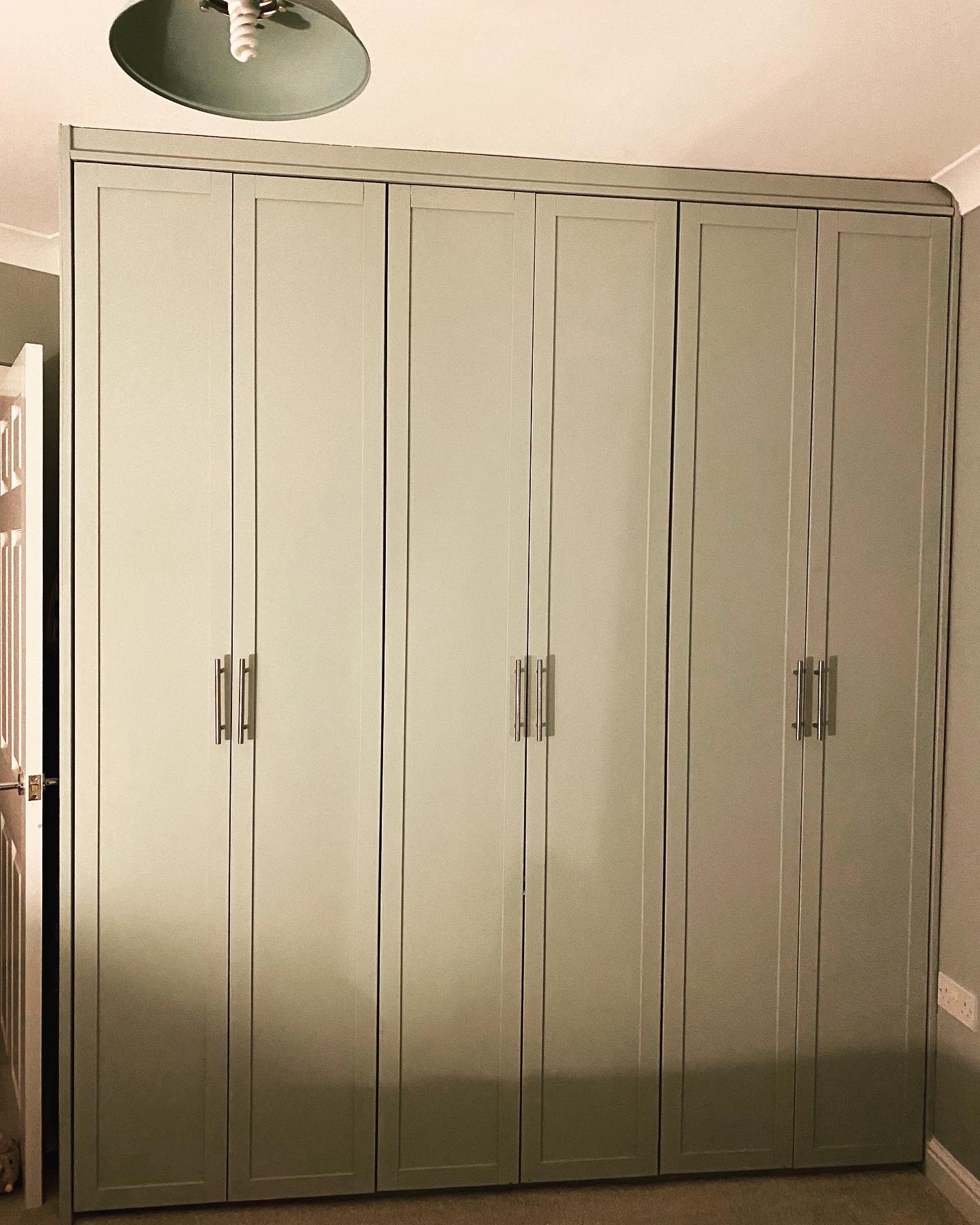 Sage green fitted wardrobes with shaker doors and long bar handles