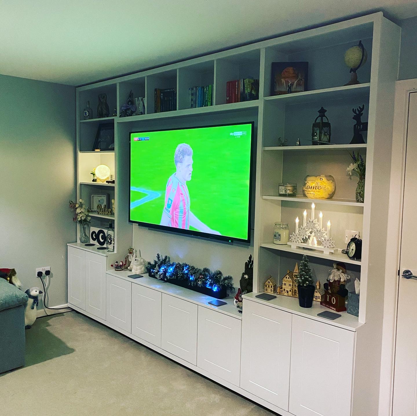 Built-in media wall with open shelving around the television and cupboards below