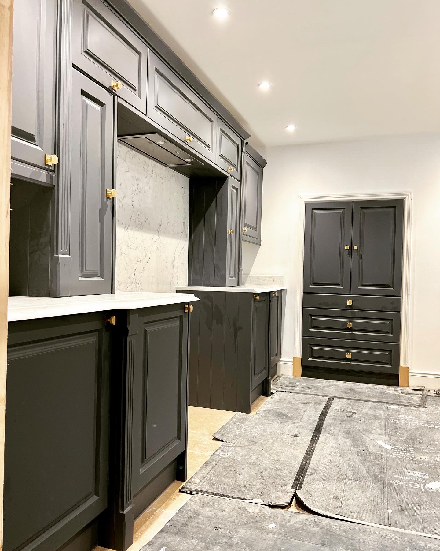 Charcoal painted kitchen units with brass knobs, part way through the fit